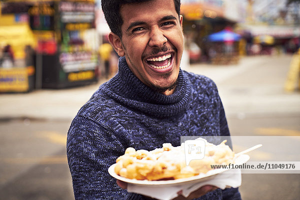 Laughing man showing plate of food at amusement park