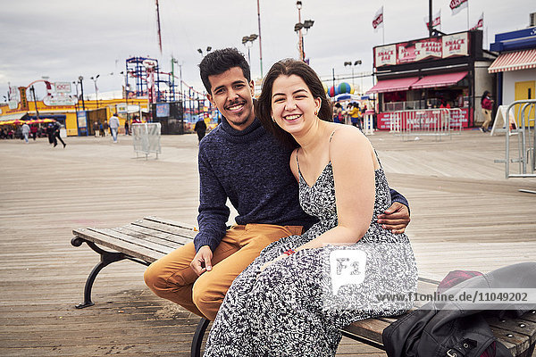 Couple sitting on boardwalk bench at amusement park