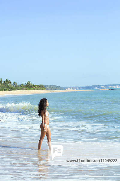 Gemischtrassige Frau geht am Strand spazieren