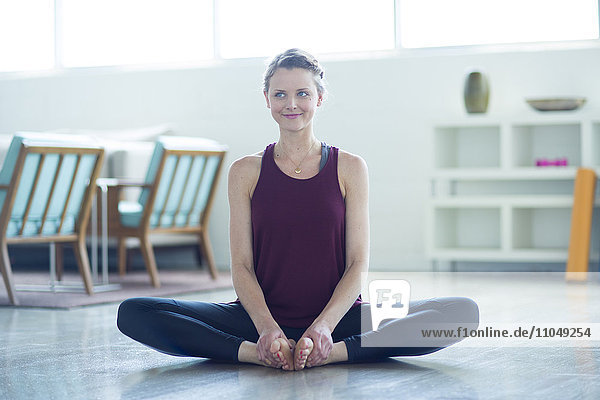 Caucasian woman sitting on floor stretching legs