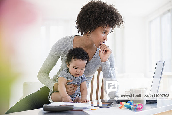 Mother holding baby son worrying about laptop