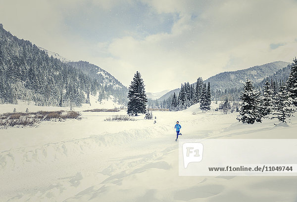 Kaukasische Frau läuft in verschneiter Landschaft