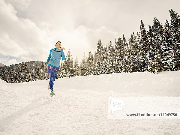Caucasian woman running in snowy landscape