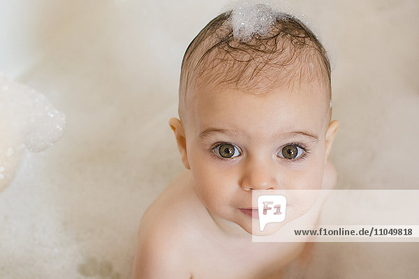 Caucasian baby girl in bathtub with soap in hair