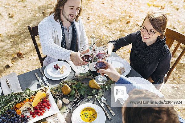 Kaukasische Freunde stoßen mit Wein an einem Tisch im Freien an