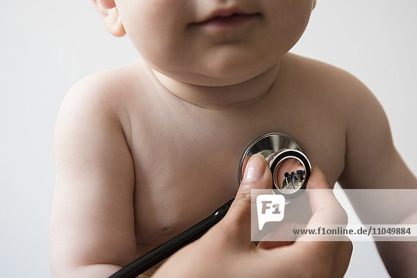 Arzt hört die Brust eines kleinen Jungen mit einem Stethoskop ab
