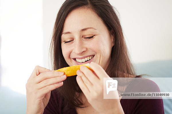 Gemischtrassige Frau isst Orange