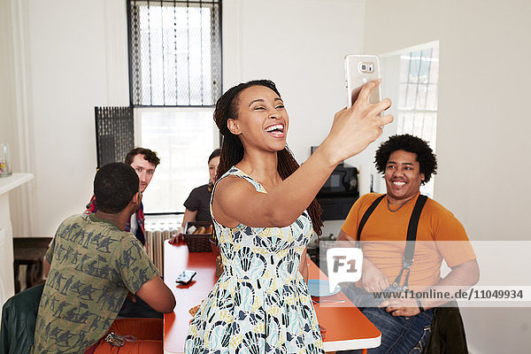 Lächelnde Frau nimmt Selfie mit Freunden