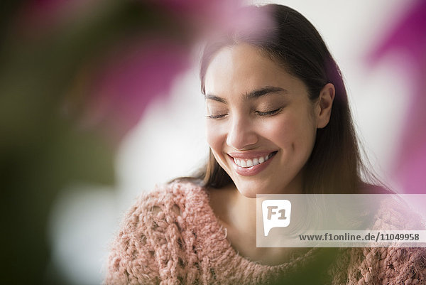 Hispanic woman smiling behind pink flowers