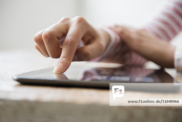 Hände einer hispanischen Frau  die ein digitales Tablet benutzt
