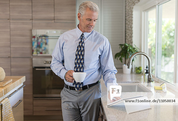 Caucasian businessman using digital tablet in kitchen