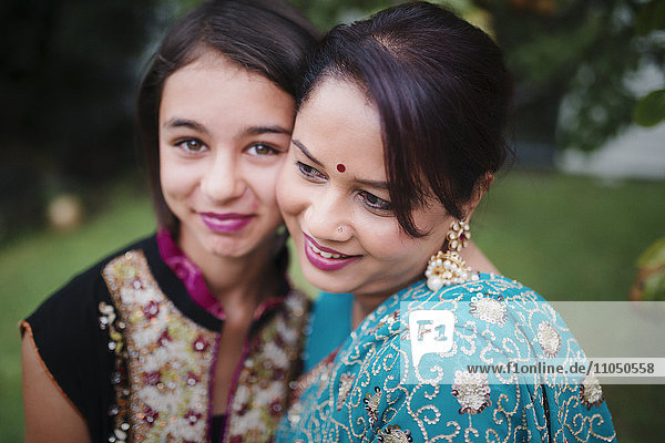 Mutter und Tochter in indischer Kleidung umarmen sich im Freien