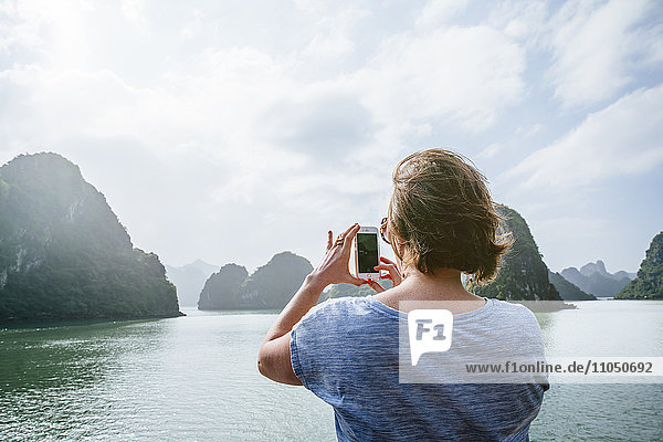 Kaukasische Frau beim Fotografieren von Felsformationen in der Ha Long Bay  Vietnam