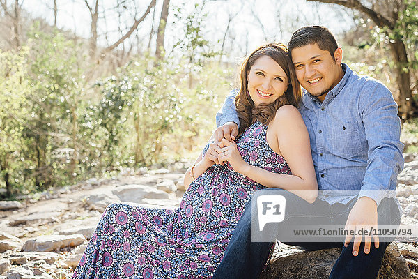 Pregnant Hispanic couple smiling outdoors