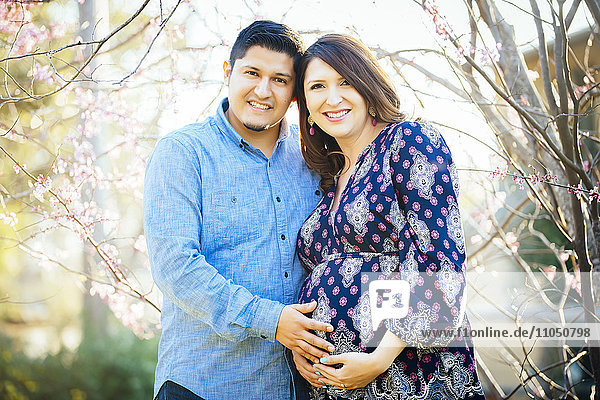 Schwangere Hispanic Paar lächelnd im Freien