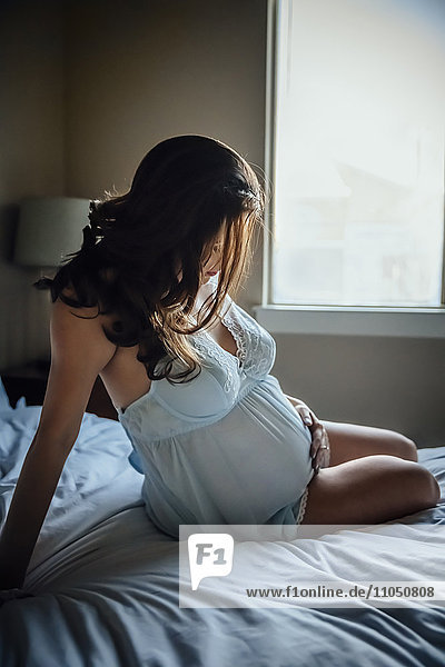 Schwangere hispanische Frau hält ihren Bauch