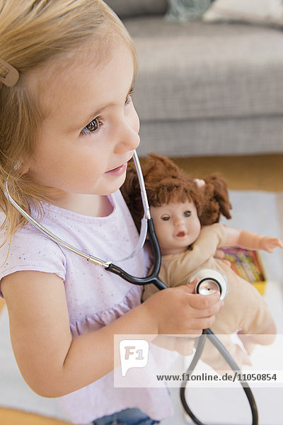 Kaukasisches Mädchen spielt Arzt mit Puppe