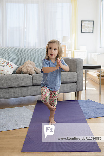 Caucasian girl practicing yoga in living room