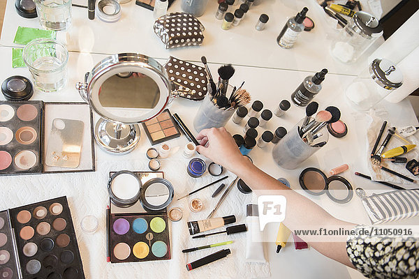 Hispanische Frau wählt Make-up vom Tisch aus