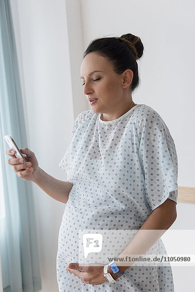 Pregnant Caucasian woman using cell phone in hospital