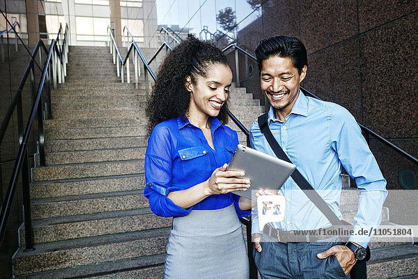 Smiling business people using digital tablet outdoors