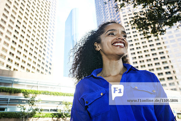 Smiling Hispanic businesswoman near highrises in city