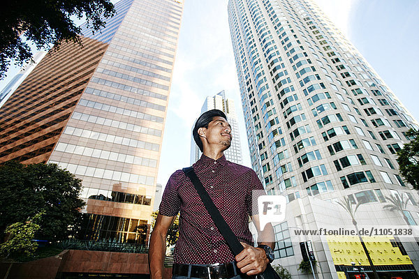 Smiling Mixed Race businessman near highrises in city