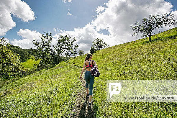 Kaukasische Frau geht auf einem Hügel und trägt eine Tasche