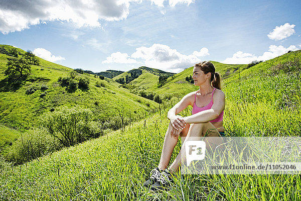 Nachdenkliche kaukasische Frau sitzt auf einem Hügel