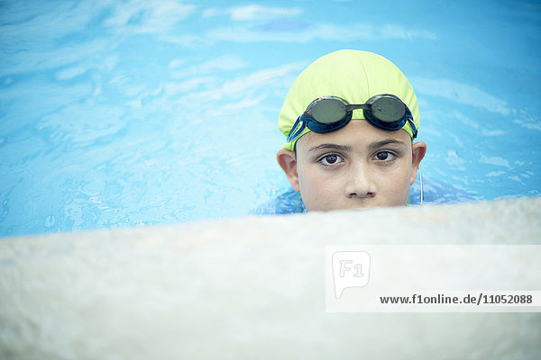 Hispanic boy swimming with swimming cap and goggles
