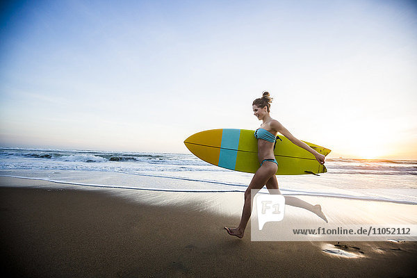 Caucasian woman carrying surfboard on beach