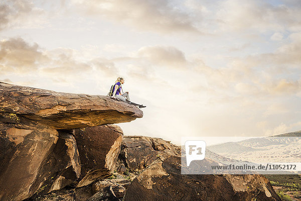 Kaukasische Frau sitzt auf einer Felsformation