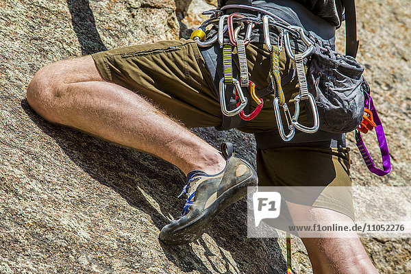 Carabiners on Caucasian man climbing rock
