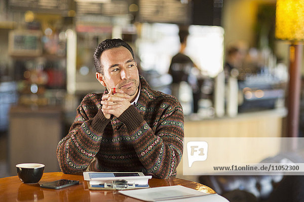 Hispanic businessman using digital tablet in coffee shop