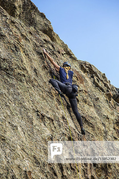 Kaukasische Frau klettert auf Felsen