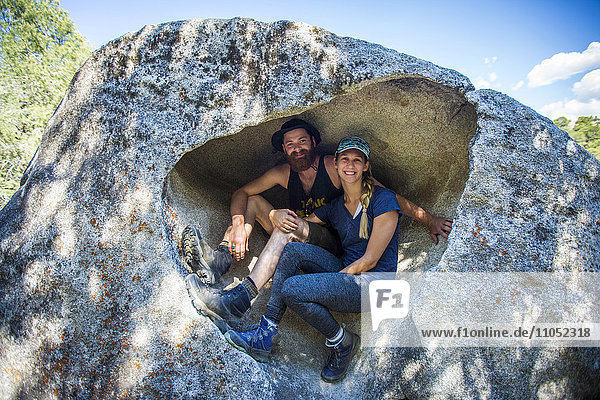 Caucasian couple sitting in rock formation