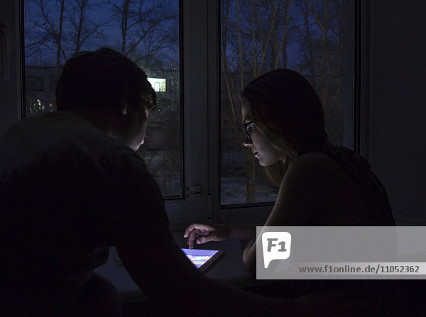 Kaukasisches Paar benutzt nachts ein digitales Tablet