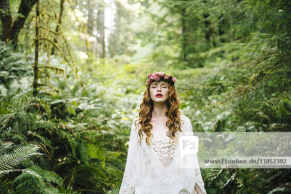 Kaukasische Frau mit Blumenkrone im Wald