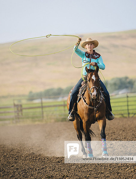Kaukasisches Cowgirl wirft Lasso auf dem Pferderücken
