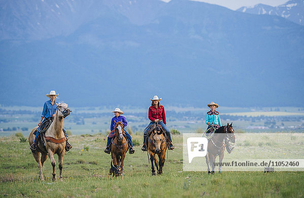 Cowboy und Cowgirls reiten auf einer Ranch