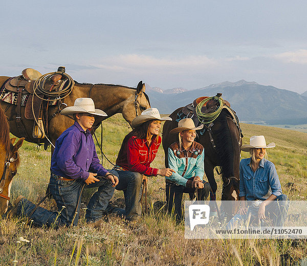 Cowboy and cowgirls with horses on ranch