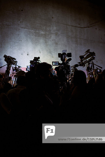 Silhouette of reporters and video cameras at press conference