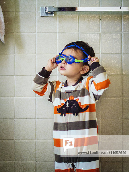 Hispanic boy playing with goggles in bathroom