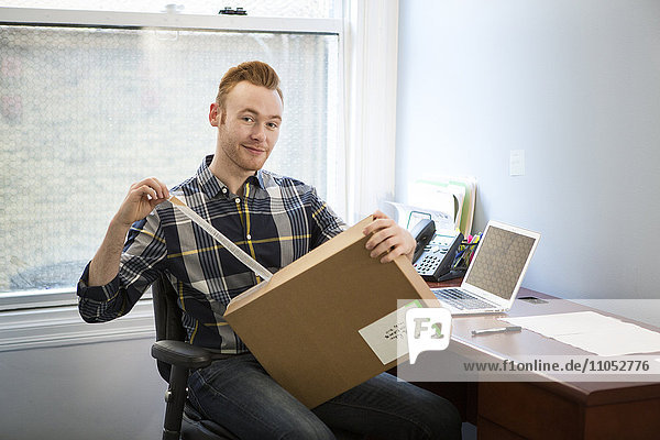 Caucasian businessman opening package in office