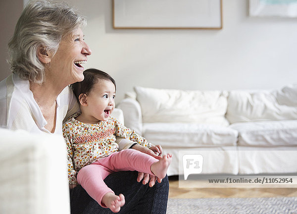 Grandmother holding granddaughter in living room