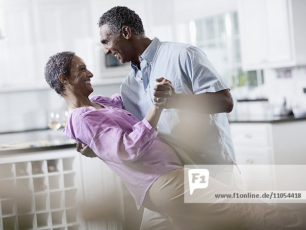 An affectionate mature African American couple  with their arms around each other dancing.