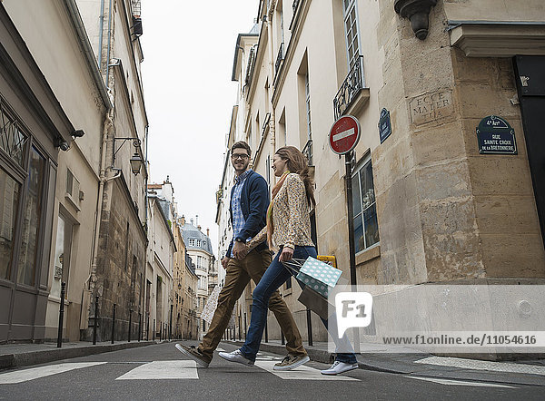 Ein Paar  das mit Einkaufstaschen durch eine schmale Straße in einem historischen Stadtzentrum geht.
