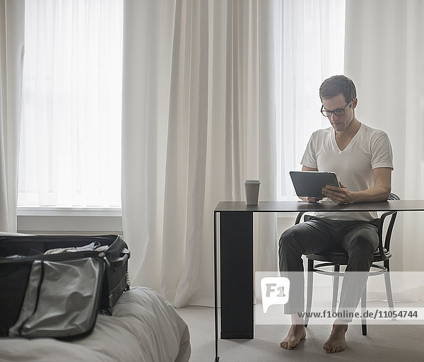 Ein Arbeitstag. Ein Mann sitzt an einem Laptop-Computer und arbeitet in einem Hotelzimmer.