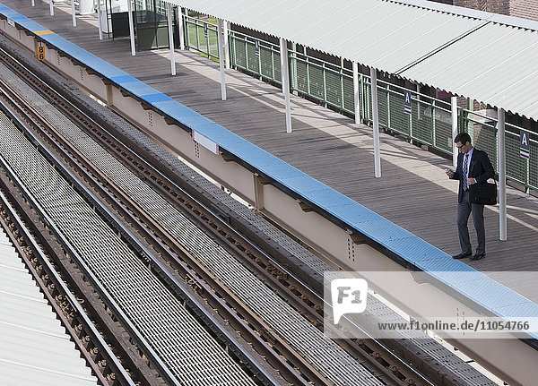 Ein Arbeitstag. Ein Blick nach unten auf einen Bahnhof und ein Mann  der auf dem Bahnsteig wartet.