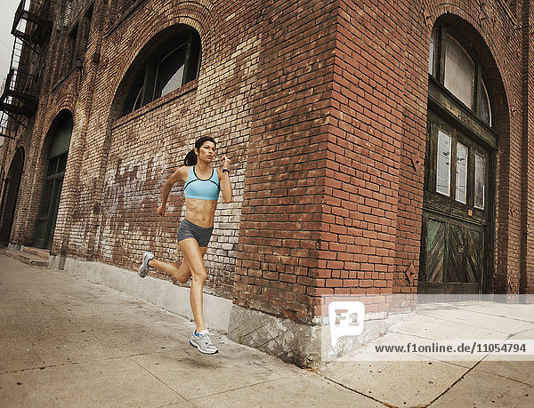 Eine Frau  die entlang einer städtischen Straße läuft  joggt  Arme und Beine streckt.